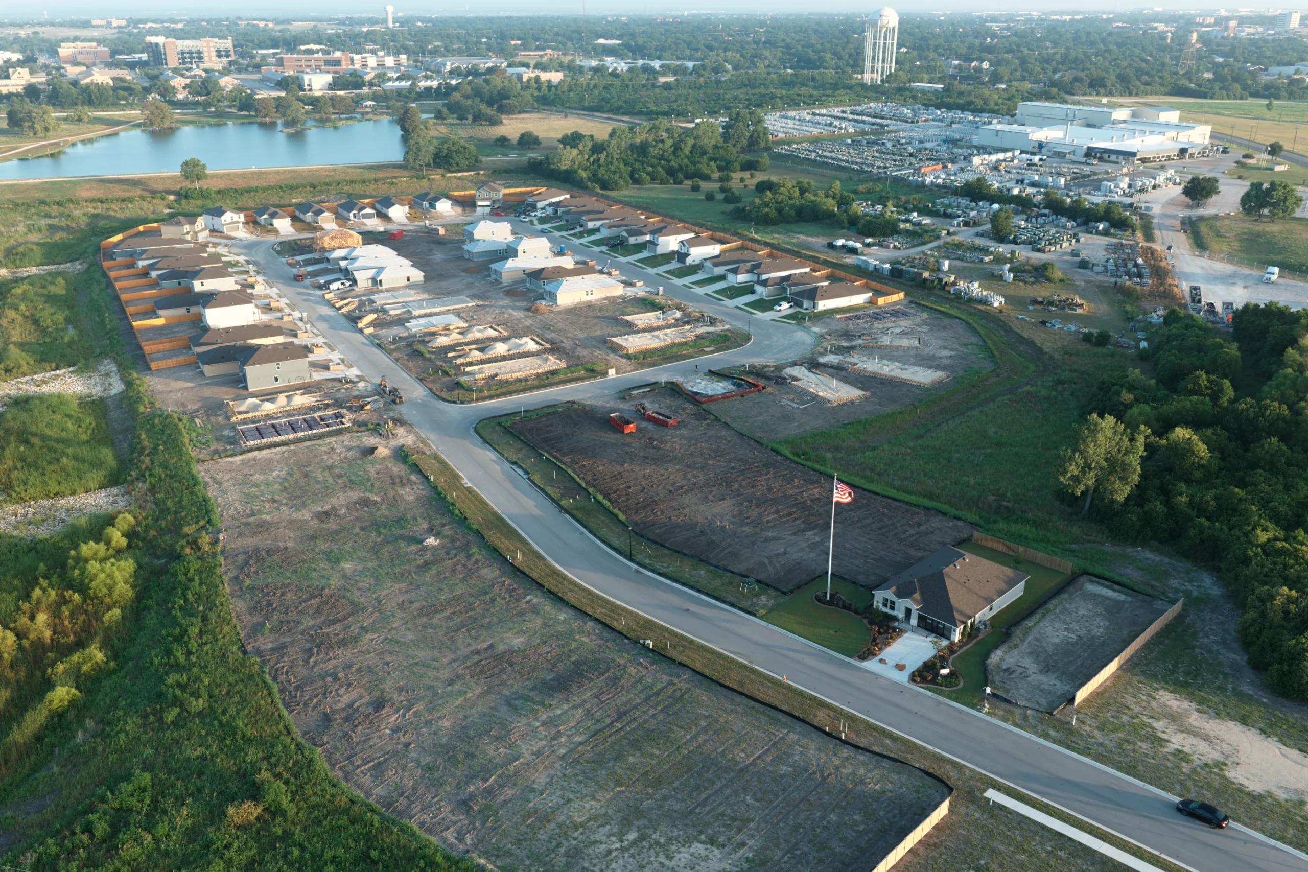 Wide aerial view of Pecan Creek showing its entrance, construction activity, surrounding roads, and nearby lake