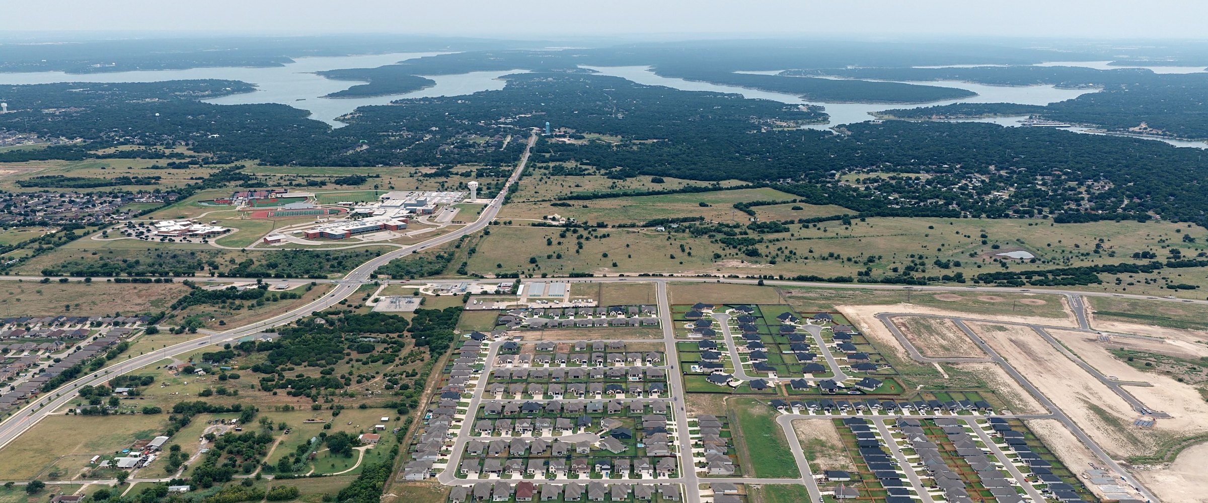 Aerial view of Mesa Ridge new construction homes in Temple TX, with Lake Belton High School and Lake Belton on the horizon