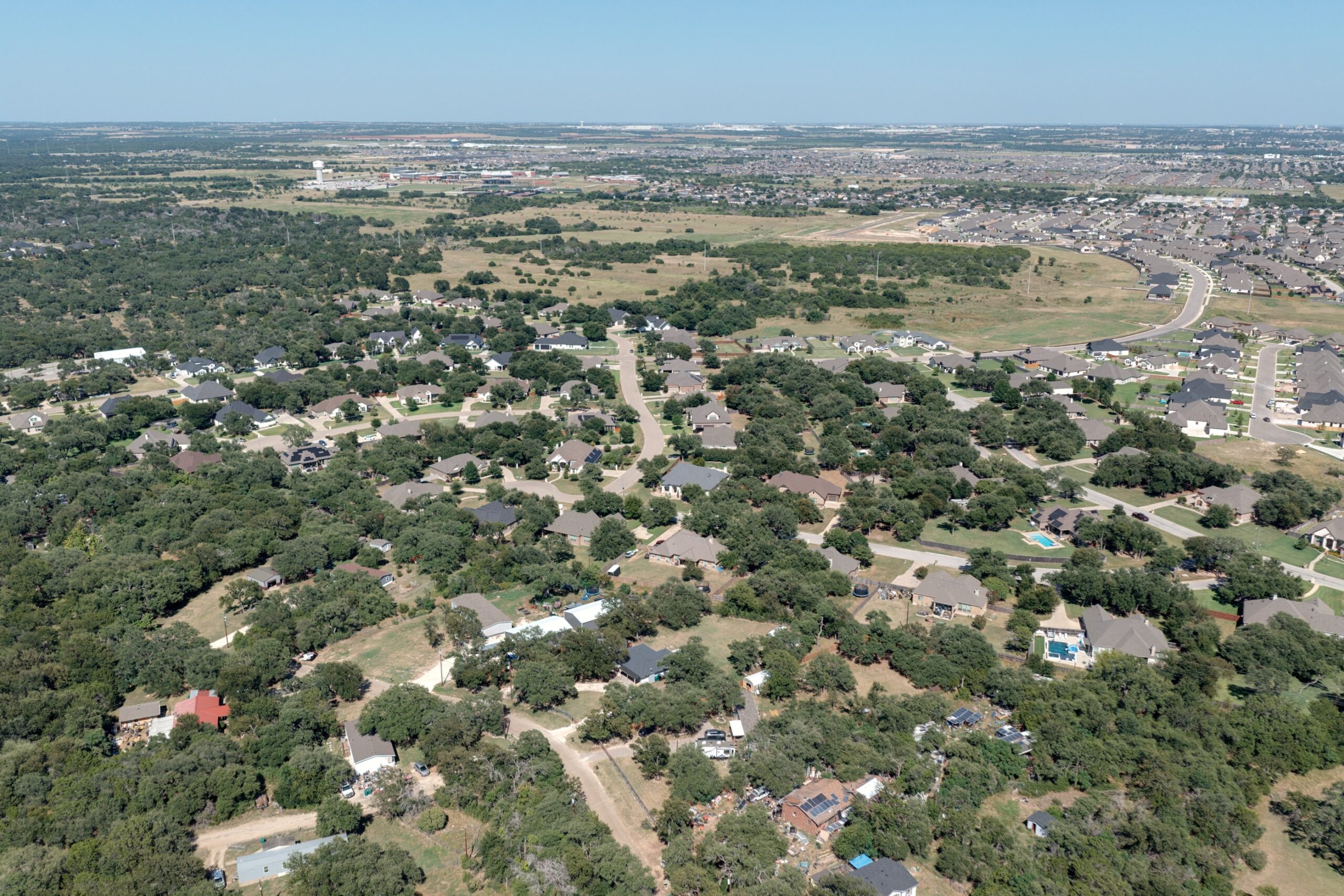 Aerial over Morgan’s Point Resort’s wooded streets, with Temple in the distance (July 2026)