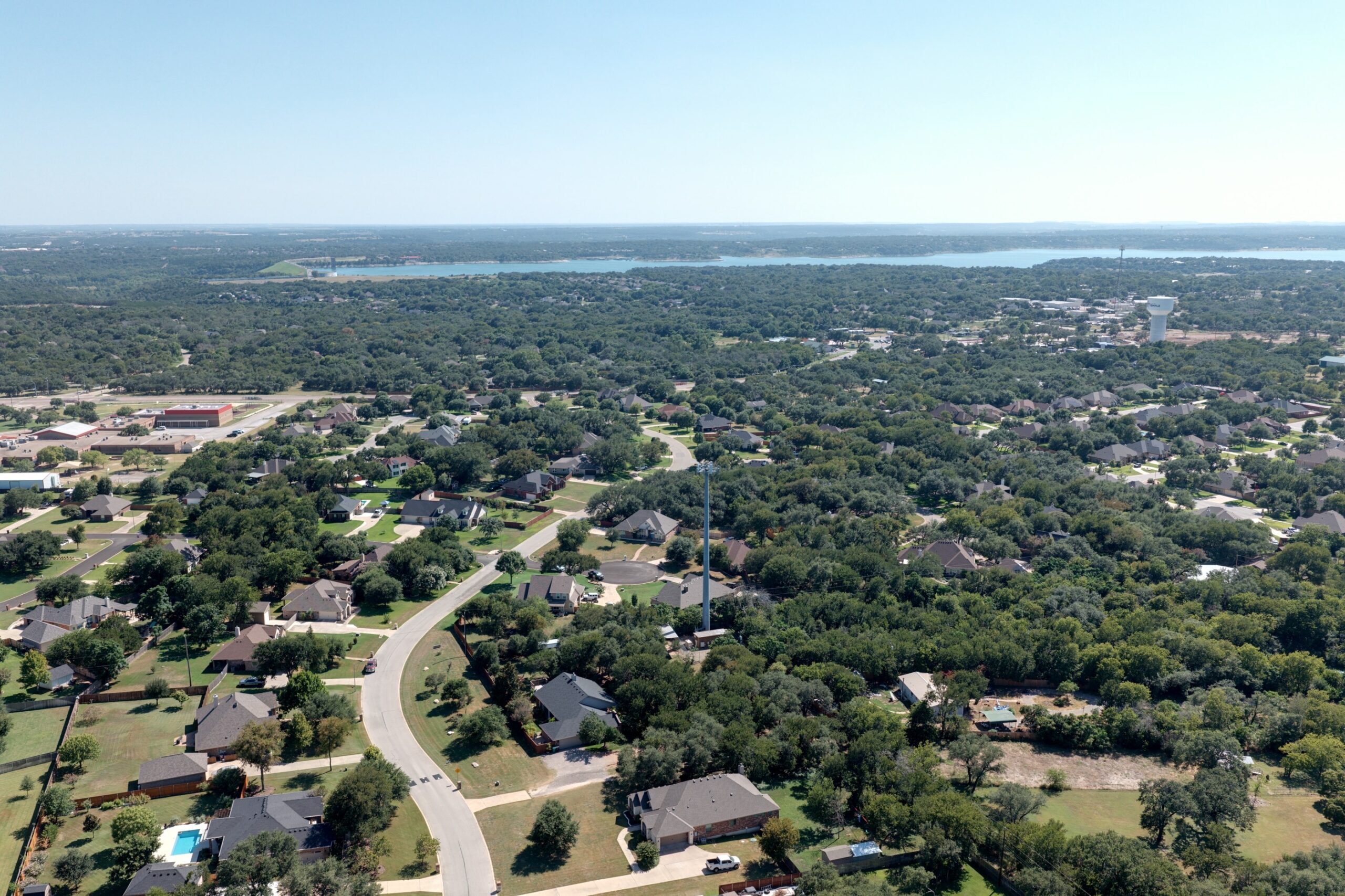 Aerial of Morgan’s Point Resort subdivisions with Belton Lake beyond — newer sections in the foreground, older lake sections toward the water (July 2026)