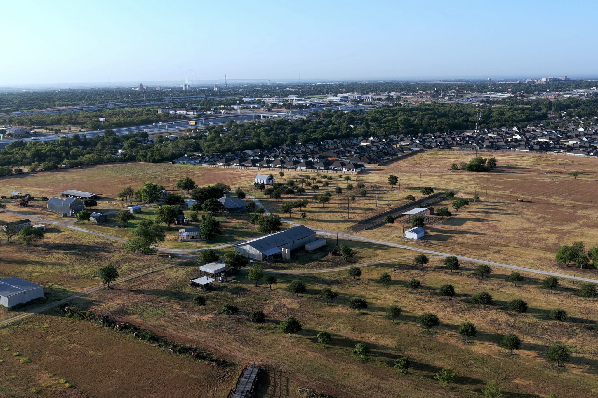 Farmland giving way to new subdivisions, with I-35 and the Temple, Texas skyline on the horizon at dawn