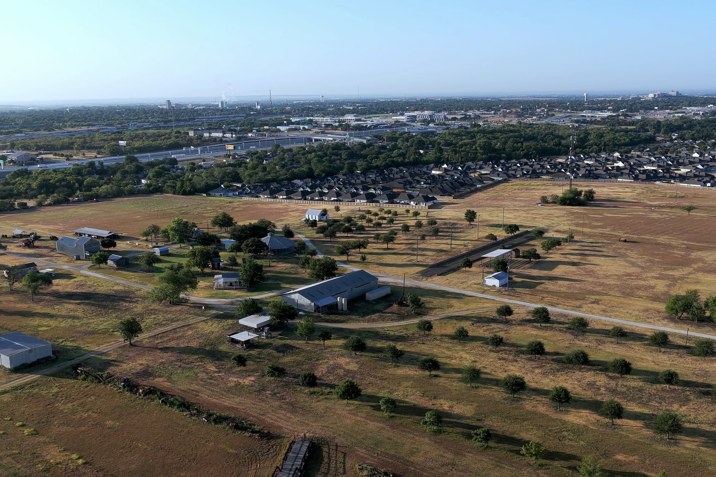 Aerial of Temple, Texas: farmland giving way to new subdivisions with the I-35 corridor and downtown skyline behind