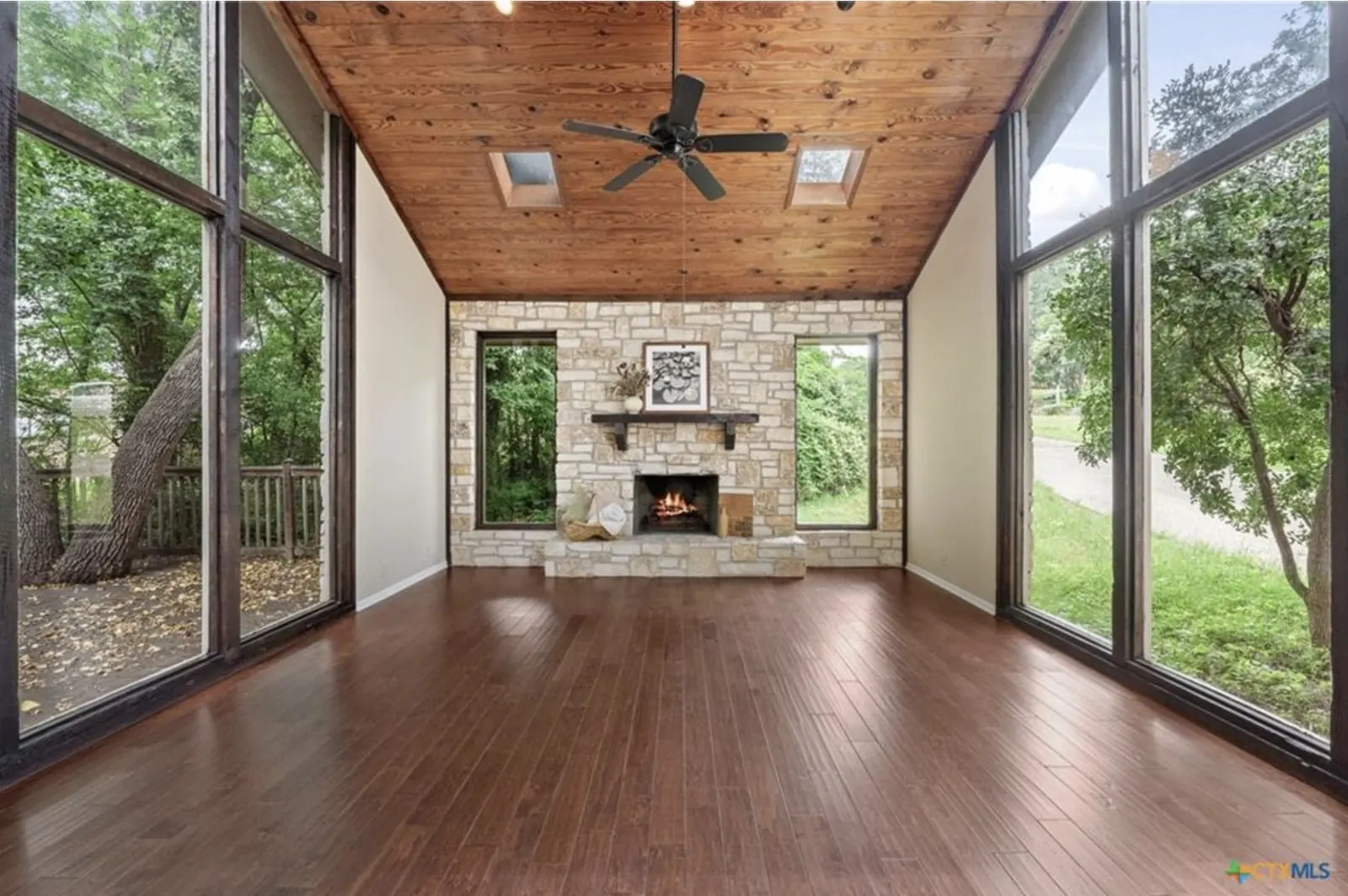 Vaulted wood ceiling, stone fireplace and floor-to-ceiling windows in a custom Canyon Creek home on a wooded lot