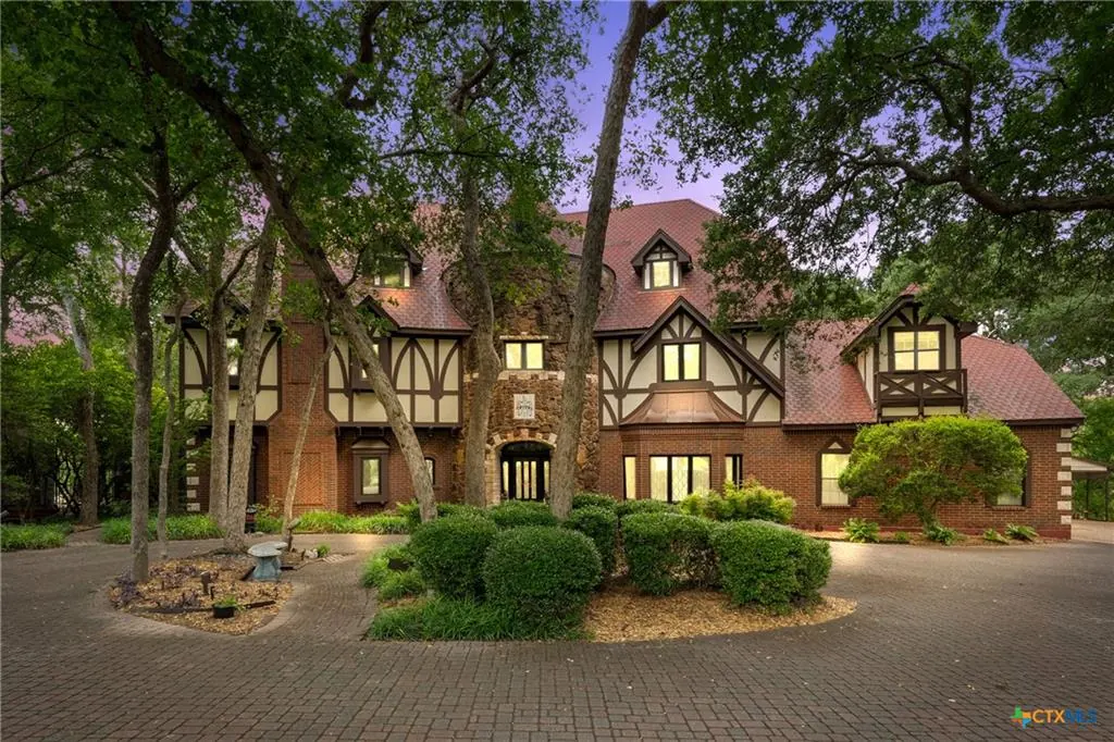 Tudor-style custom estate at dusk on a wooded lot in the Cliffs of Canyon Creek, Temple TX
