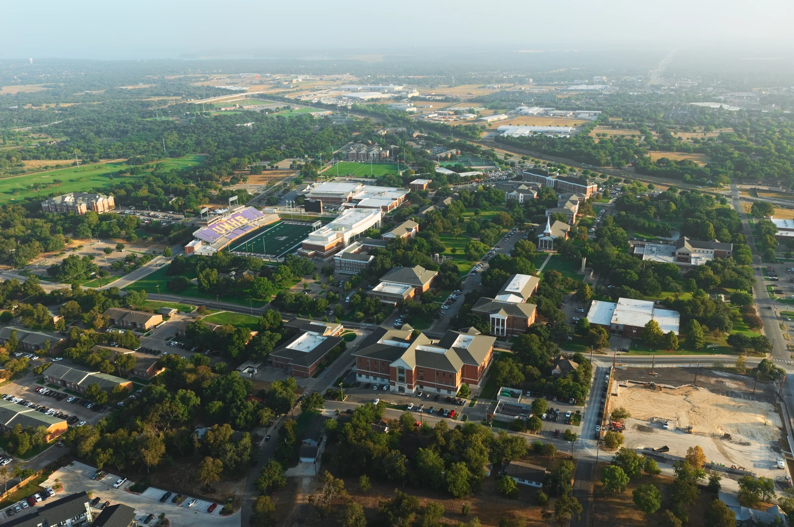UMHB campus in Belton, with the stadium, campus buildings, tree-lined grounds and city beyond.