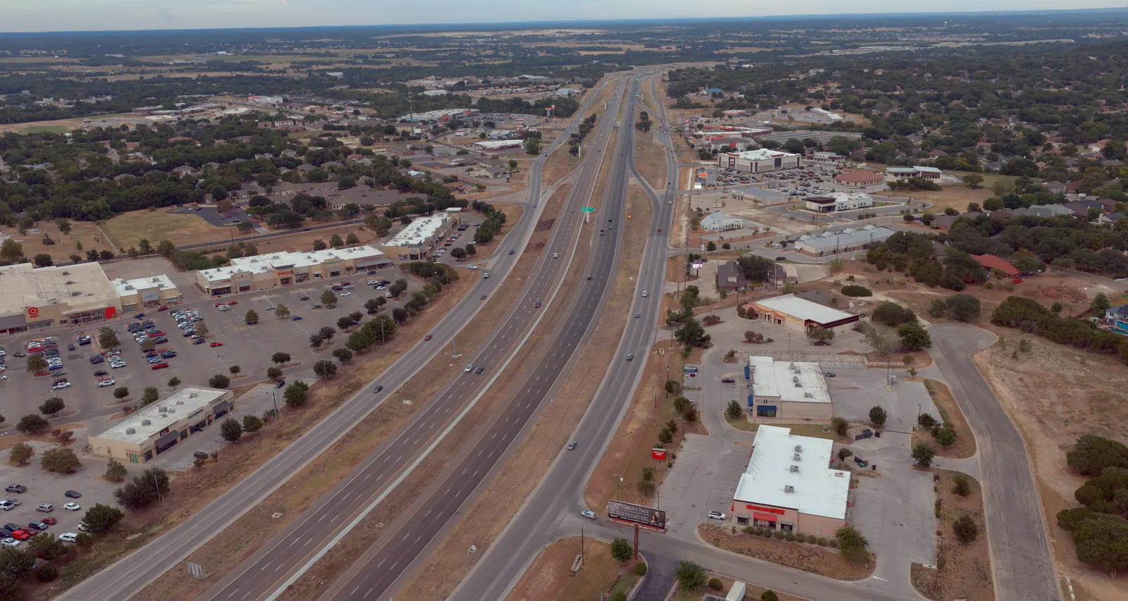 Aerial view of I-14/US 190, the Central Texas Expressway, through Harker Heights, Texas: frontage roads, shopping centers and neighborhoods on both sides of the freeway, running to the horizon in the evening light.