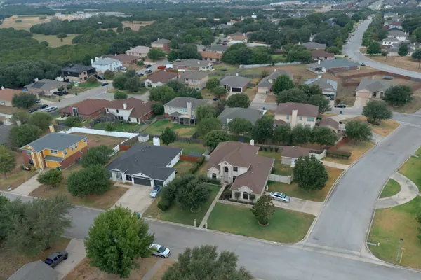 Aerial view of a residential street in Harker Heights, Texas: brick and stone homes, mature trees and a curving street.