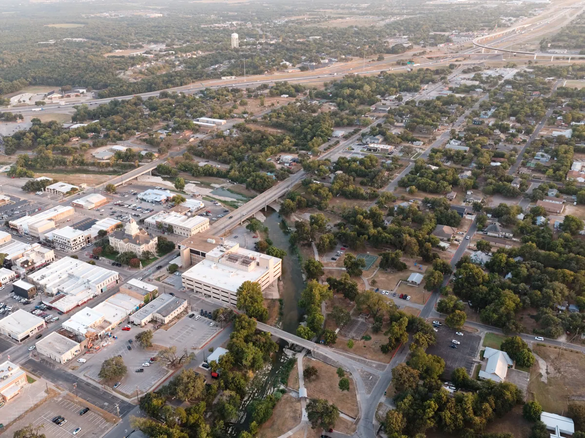 Aerial view of downtown Belton, Texas: Nolan Creek and its bridges in the foreground, the Bell County Courthouse and downtown, and I-35 with its I-14 interchange beyond.
