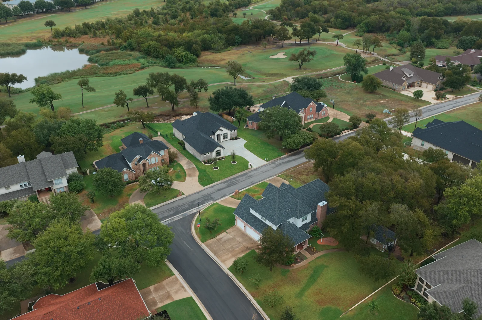 Homes along a residential street beside fairways and a pond in the Wildflower area.